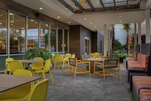 莱克兰Home2 Suites By Hilton Lakeland的餐厅设有黄色的椅子和桌子以及窗户。