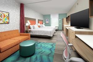 莱克兰Home2 Suites By Hilton Lakeland的酒店客房配有床、沙发和电视。