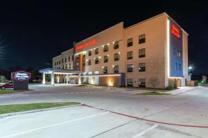 达拉斯Hampton Inn & Suites Dallas East的夜间酒店大楼,设有停车场