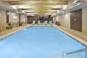 霍兰Home2 Suites By Hilton Holland的一个带桌椅的房间的大型游泳池
