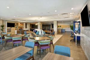 普莱诺Home2 Suites Plano Legacy West的一间带桌椅的餐厅和一间酒吧