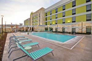 普莱诺Home2 Suites Plano Legacy West的大楼前带躺椅的游泳池