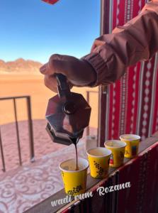 瓦迪拉姆Wadi rum Rozana camp的把酒从两个杯子里拿出来的人