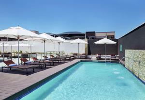 哈博罗内Hilton Garden Inn Gaborone, Botswana的一座大楼内的游泳池,配有椅子和遮阳伞