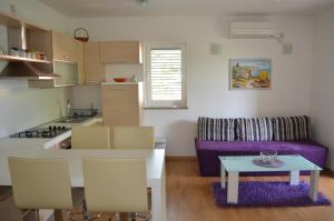 巴斯卡Apartments Soldo的厨房以及带桌子和紫色沙发的客厅。