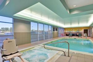 爱达荷福尔斯Tru By Hilton Idaho Falls Id的游泳池,带椅子,位于酒店房间