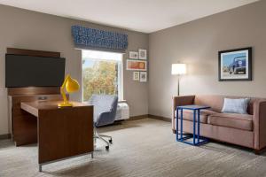 大洋城Hampton Inn & Suites Ocean City West的酒店客房设有一张沙发和一张带电视的书桌。