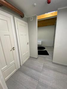 DrustiDrustu atpūtas nams Magazīna的走廊设有两扇白色门,铺有瓷砖地板