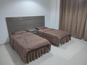 塞拉莱رحاب السعاده rehab alsaadah apartment的客房内的两张床和棕色毯子