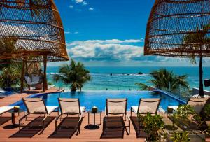 莫罗圣保罗Pousada Bahia Tambor的一个带椅子的游泳池,背景是大海