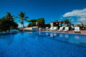 莫罗圣保罗Pousada Bahia Tambor的一个带椅子和棕榈树的大型游泳池