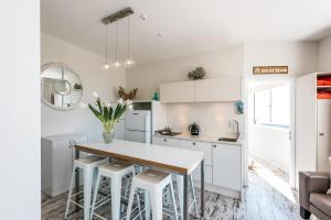欧尼罗亚Oneroa Central - Coast & Country的厨房配有白色橱柜、桌子和凳子