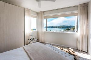 欧尼罗亚Oneroa Central - Coast & Country的一间卧室设有大窗户,享有水景