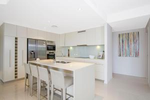 金斯克里福Terrace 5 - Kingscliff Oceanview的一间带白色橱柜的厨房和一个带椅子的厨房岛