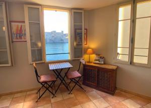 科利尤尔Résidence Collioure Plage的客房设有两把椅子、一张桌子和一个窗户。