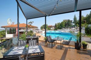 索佐波尔Viva Mare Beach Hotel by Santa Marina的一个带桌椅的甲板和一个游泳池