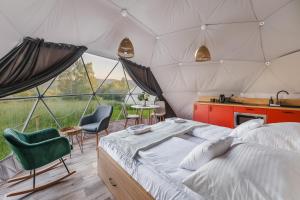 ManiowyBiała Czapla Glamping z balią nad jeziorem czorsztyńskim的一间卧室,在帐篷里配有一张床和椅子