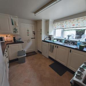 斯莱戈Clover Cottage的厨房配有白色橱柜、水槽和窗户。