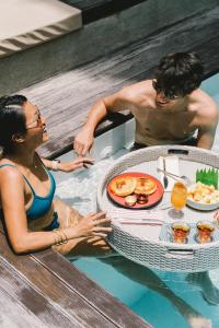 爱妮岛Panorama Villas El Nido的坐在游泳池里带餐桌的男人和女人