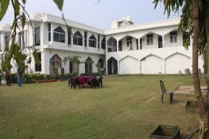 珀勒德布尔The Hotel Raj Palace的一座带桌椅的大型白色建筑,位于庭院内