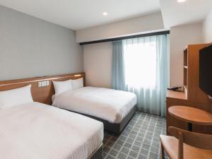 神户Sotetsu Fresa Inn Kobe Sannomiya的酒店客房设有两张床和窗户。