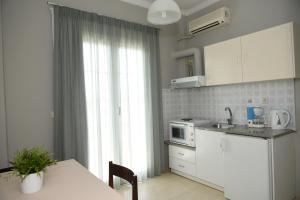 托隆斯卡丽迪斯公寓的厨房配有白色橱柜、桌子和窗户。