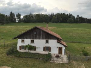 Le Noirmontla ferme de la gaby的一块白色房子,在田野上有一个棕色的屋顶