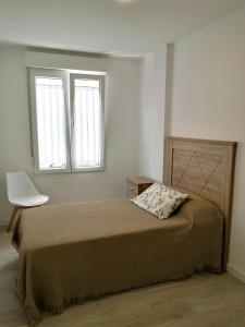 费罗尔Alojamiento céntrico con encanto的一间卧室配有一张带椅子的床和两个窗户