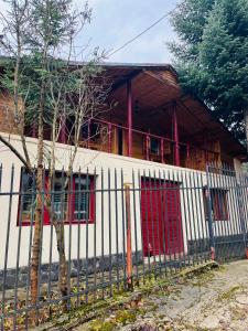 普雷代亚尔Casuta noastra din Predeal的白色的房子,设有红色的窗户和栅栏
