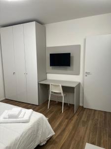 圣佩莱格里诺温泉San Pellegrino Suites的一间卧室配有一张床和一张书桌及电视