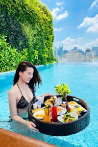 胡志明市西贡天堂精品Spa酒店的坐在游泳池里带餐盘的女人