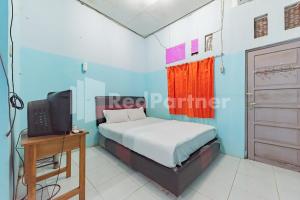 BanjarbaruAna Guest House Syariah Mitra RedDoorz的一间卧室配有一张床、一张书桌和一台电视。