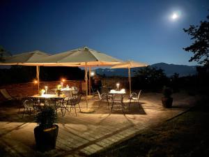 Mombello Monferrato坎迪内塔度假酒店的一组桌子和椅子在晚上伞下