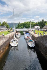 奥古斯都堡Loch Ness Gate House的三条船停靠在运河里,人们在运河里散步