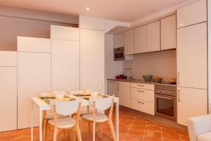 塔维拉Casa do Terreiro的厨房配有白色橱柜和桌椅
