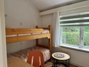 HummeloAchterhoekhuisje De Rode Beuk的一间卧室配有一张双层床、一张桌子和一个窗户。