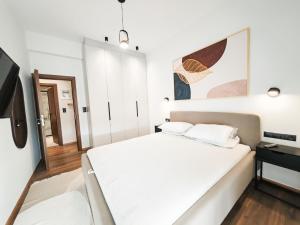 雅典AKO12 Central Athens Metaxurgio Apartment的一间白色卧室,配有床和电视