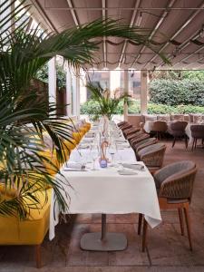 穆拉诺Hyatt Centric Murano Venice的餐厅里长长的白色桌子,有椅子和植物