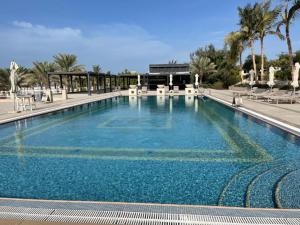 拉斯阿尔卡麦I Like Al Hamra Palace - Elite Beach & Golf Resort Private Suites的一个带椅子和棕榈树的大型蓝色游泳池