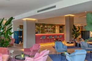 西尔米奥奈Olivi Hotel & Natural Spa的大堂设有粉红色和蓝色的椅子,酒吧