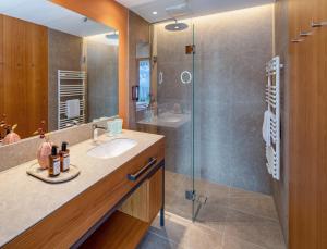 施伦斯Falkensteiner Family Hotel Montafon - The Leading Hotels of the World的一间带水槽和玻璃淋浴的浴室