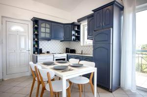 科罗尼Koroni Xenios Zeus, Seaview Summer Retreats的厨房配有蓝色橱柜和白色的桌椅