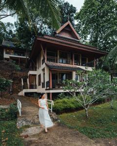 象岛Kooncharaburi Resort - Koh Chang的站在房子前面的穿着白色衣服的女人