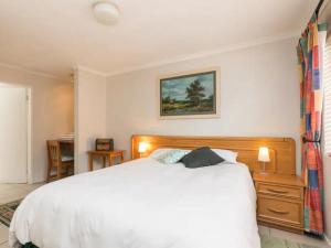 约翰内斯堡Parkhurst Cottage的卧室配有一张白色大床和一张书桌