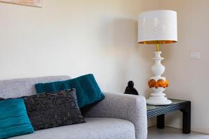 里乔内Prime blue suite - Giardini的坐在沙发旁边的桌子上的一盏灯