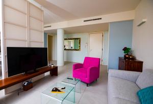 里乔内Prime blue suite - Giardini的客厅配有粉红色的椅子和电视