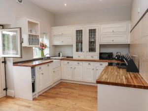 韦克菲尔德The Moorings的厨房铺有木地板,配有白色橱柜。
