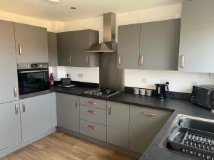 德比Kingsway House - Brand New Spacious 4 Bed Home From Home的厨房配有灰色和白色的橱柜和水槽