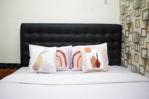 梭罗Capital O 2258 Santana Syariah Guest House的一张带四个枕头和黑色床头板的床