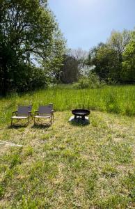 TanderupMellem-rummet Guesthouse & Glamping的田野上的两把椅子和一张野餐桌